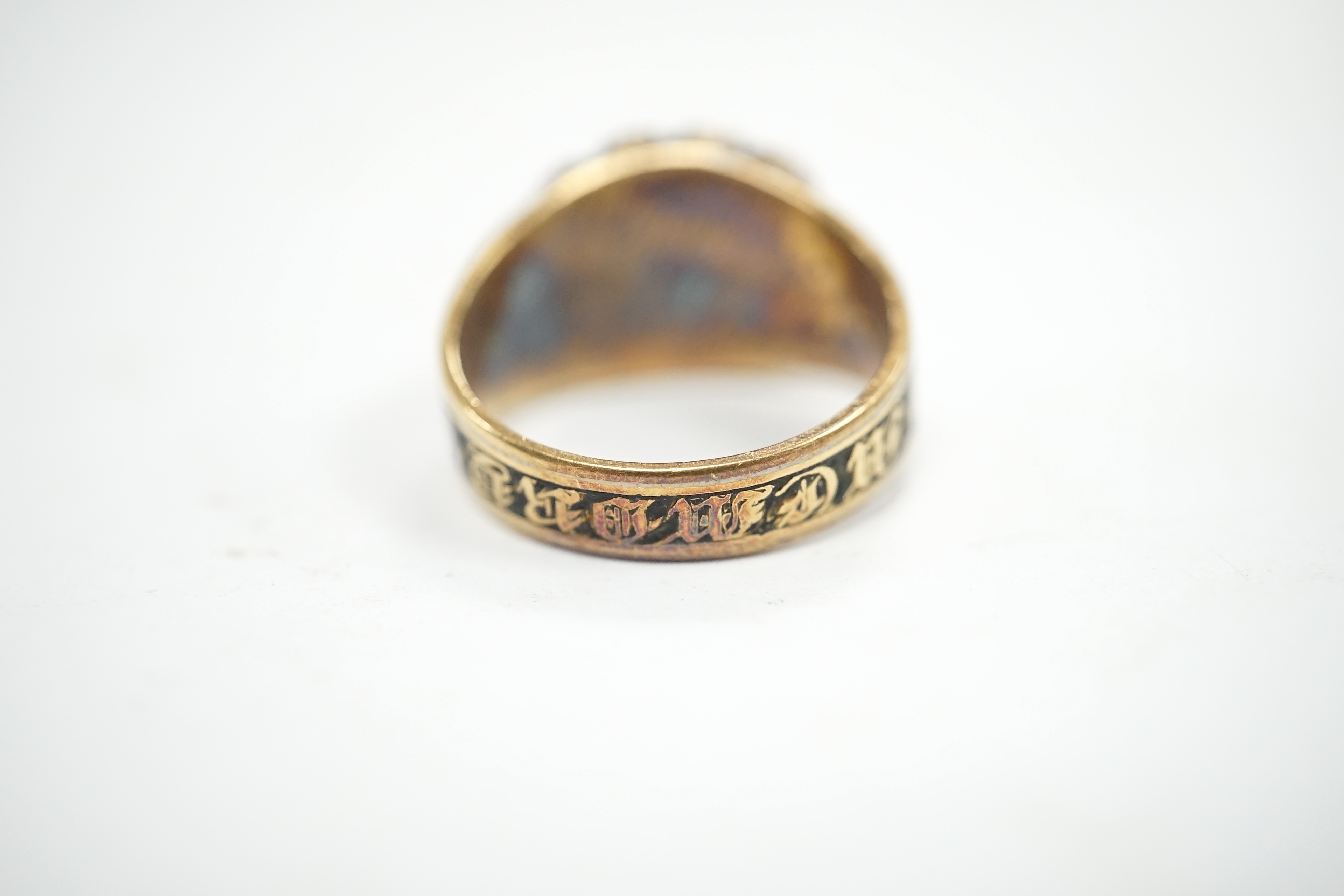 A late George III yellow metal, two colour enamel and split pearl set mourning ring, with plaited hair beneath a glazed panel, inscribed, 'M.J. Escott died 12th July, 1817 aged 21', size N, gross weight 6.8 grams. Condit